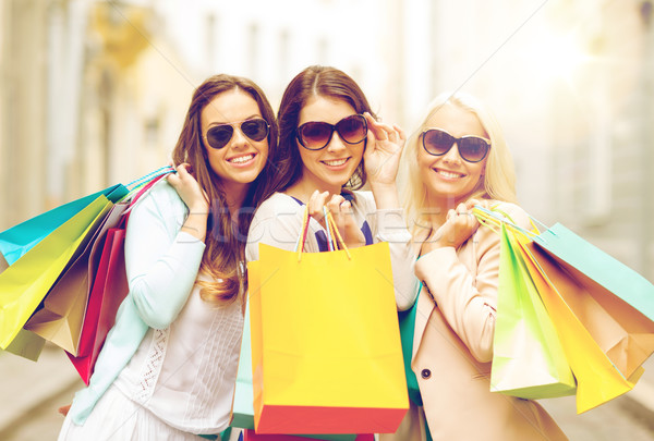 Stock photo: three smiling girls with shopping bags in ctiy