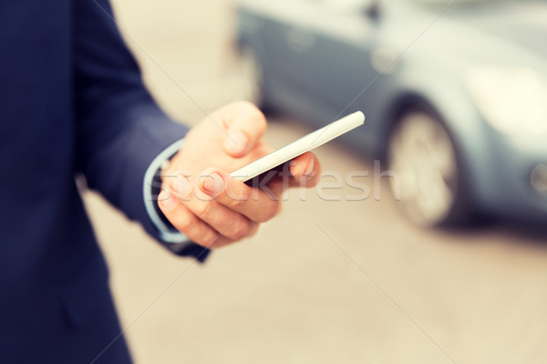 Stock photo: close up of man hand with smartphone and car