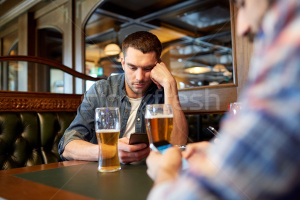 men with smartphones drinking beer at bar or pub Stock photo © dolgachov