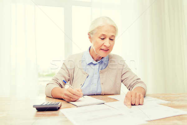 senior woman with papers and calculator at home Stock photo © dolgachov