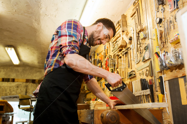 carpenter working with saw and wood at workshop Stock photo © dolgachov
