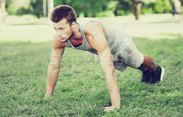 Stock photo: young man doing push ups on grass in summer park