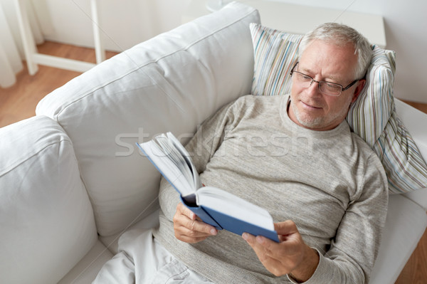 senior man lying on sofa and reading book at home Stock photo © dolgachov