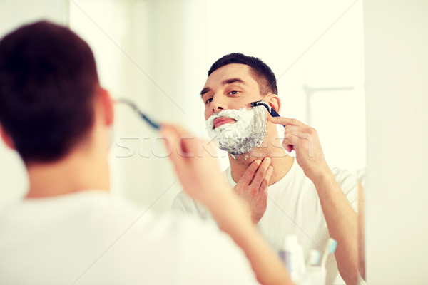 man shaving beard with razor blade at bathroom Stock photo © dolgachov