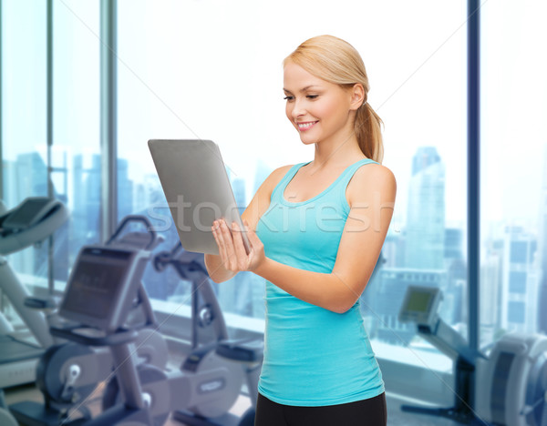 smiling sporty woman with tablet pc in gym Stock photo © dolgachov