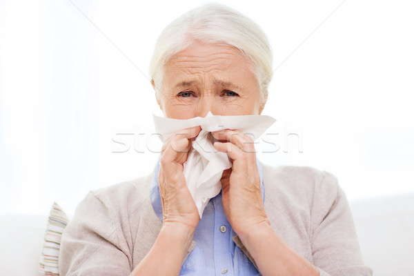 sick senior woman blowing nose to paper napkin Stock photo © dolgachov