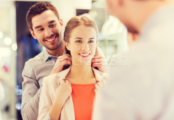 Stock photo: couple trying golden pendant on at jewelry store