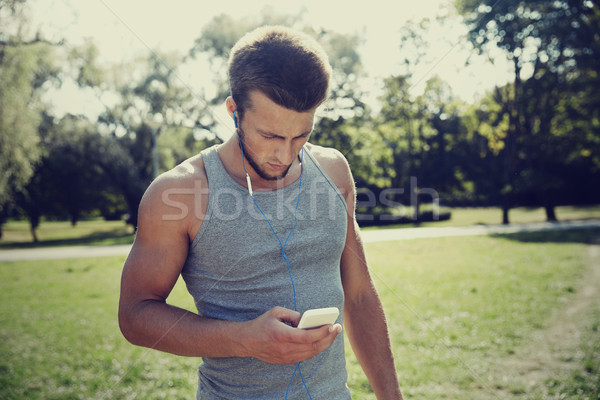 Fiatalember fülhallgató okostelefon park fitnessz sport Stock fotó © dolgachov