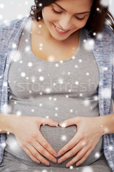 happy pregnant woman making heart gesture at home Stock photo © dolgachov