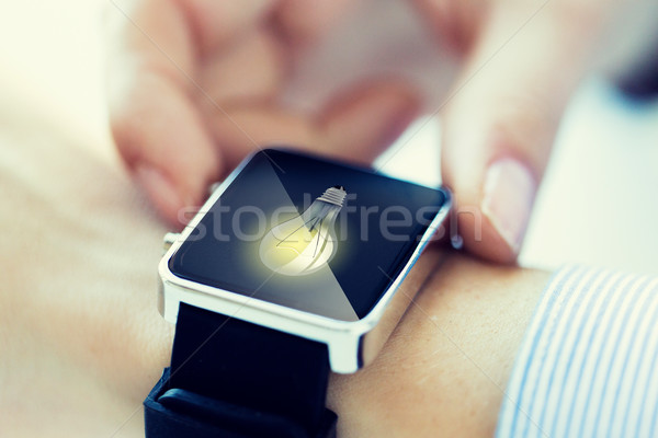 close up of hands with lightbulb on smartwatch Stock photo © dolgachov