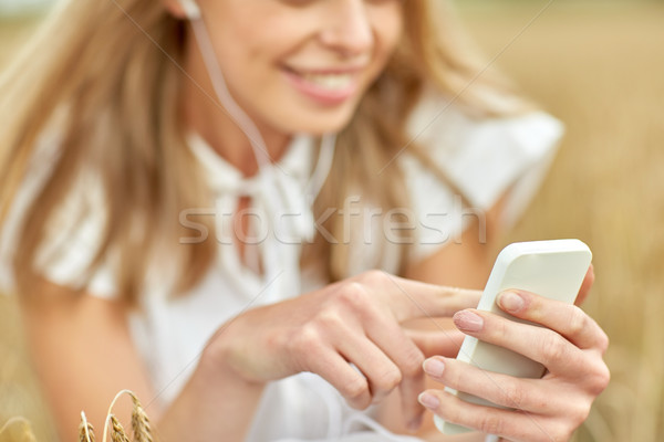 Stock photo: close up of woman with smartphone and earphones