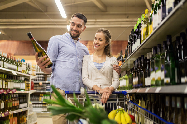 couple with wine and shopping cart at liquor store Stock photo © dolgachov