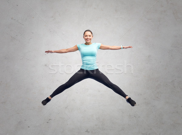 Stock photo: happy smiling sporty young woman jumping in air