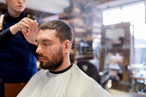 barber applying styling spray to male hair Stock photo © dolgachov