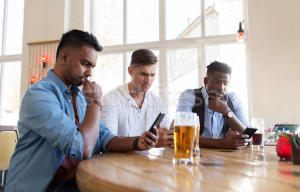 Stockfoto: Mannelijke · vrienden · smartphone · drinken · bier · bar