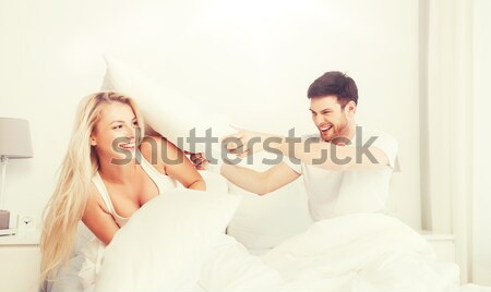 Heureux couple bataille d'oreillers lit maison personnes [[stock_photo]] © dolgachov