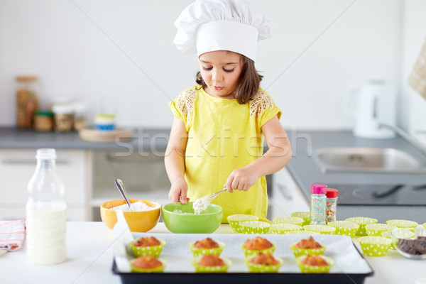 Stock photo: little girl in chefs toque baking muffins at home