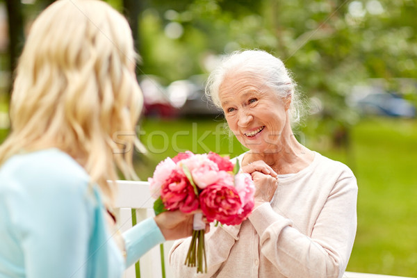 daughter giving flowers to senior mother at park Stock photo © dolgachov