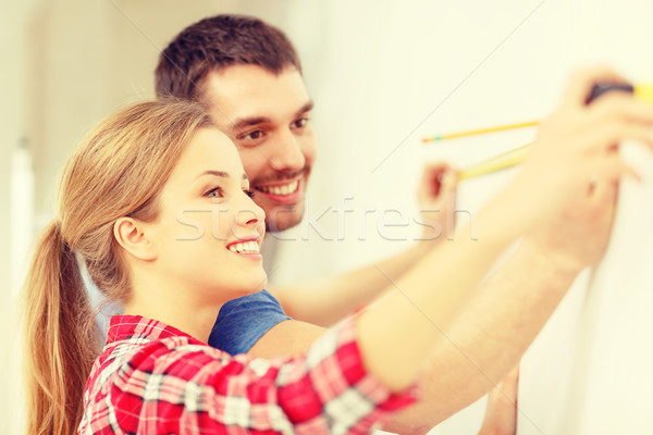 smiling couple measuring wall Stock photo © dolgachov