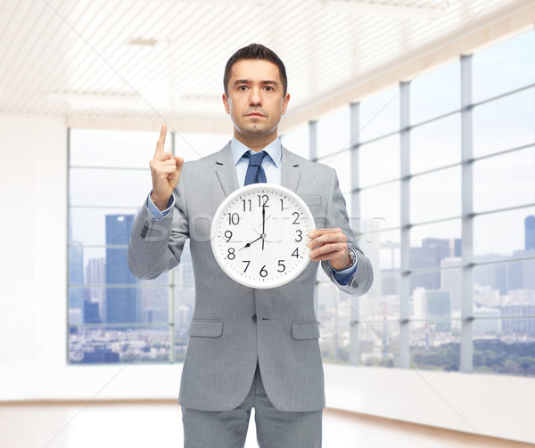 Stock photo: businessman in suit holding clock with 8 o'clock