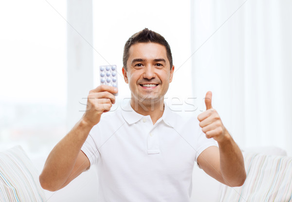happy man with pack of pills showing thumbs up Stock photo © dolgachov