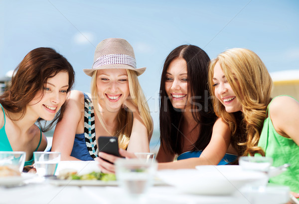 girls looking at smartphone in cafe on the beach Stock photo © dolgachov
