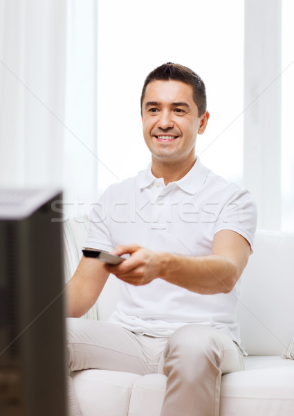 улыбаясь человека пультом смотрят телевизор домой Сток-фото © dolgachov