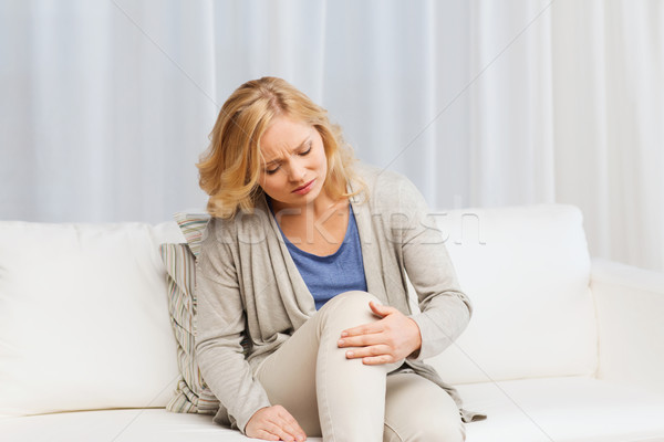 unhappy woman suffering from pain in leg at home Stock photo © dolgachov