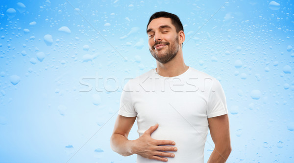 happy full man touching tummy over blue background Stock photo © dolgachov