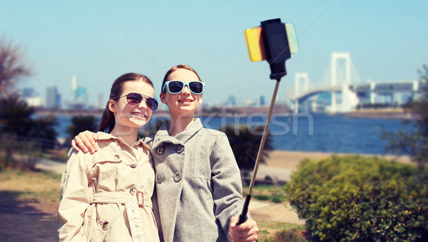 happy girls with smartphone selfie stick in tokyo Stock photo © dolgachov