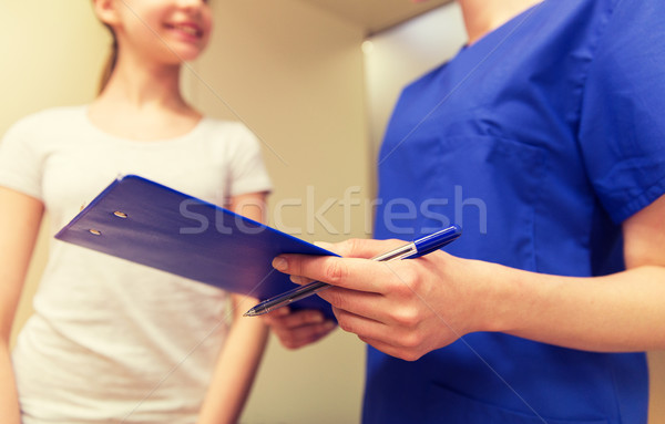 close up of nurse with clipboard and pen with girl Stock photo © dolgachov