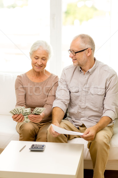 Stock photo: senior couple with money and calculator at home