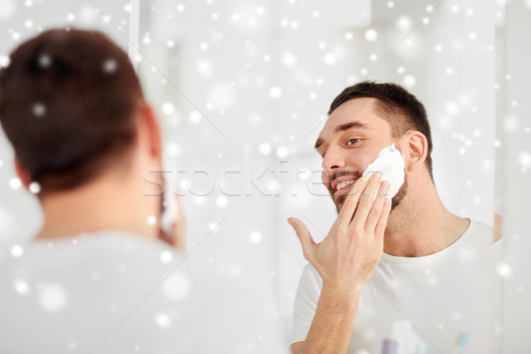 happy man applying shaving foam at bathroom mirror Stock photo © dolgachov