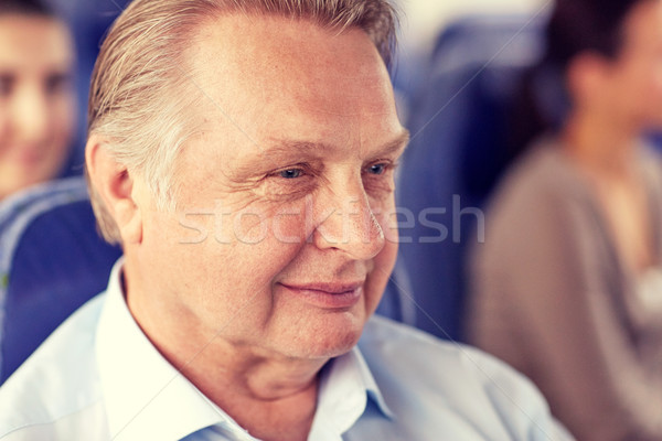 happy senior man sitting in travel bus or airplane Stock photo © dolgachov