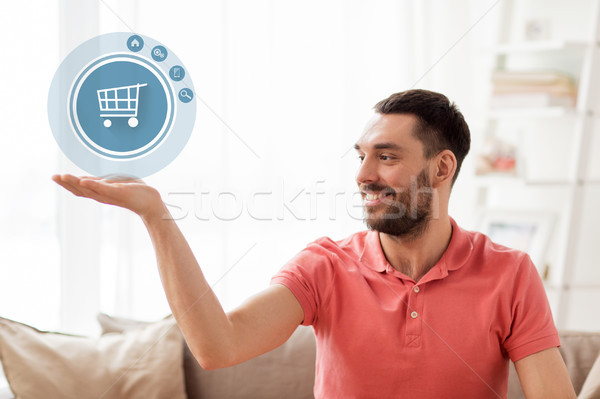 man with shopping cart icon projection at home Stock photo © dolgachov