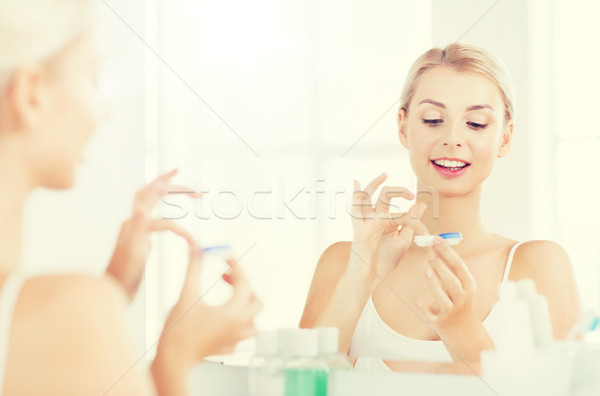 Stock photo: young woman putting on contact lenses at bathroom