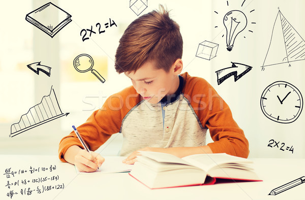 Stock photo: student boy with book writing to notebook at home