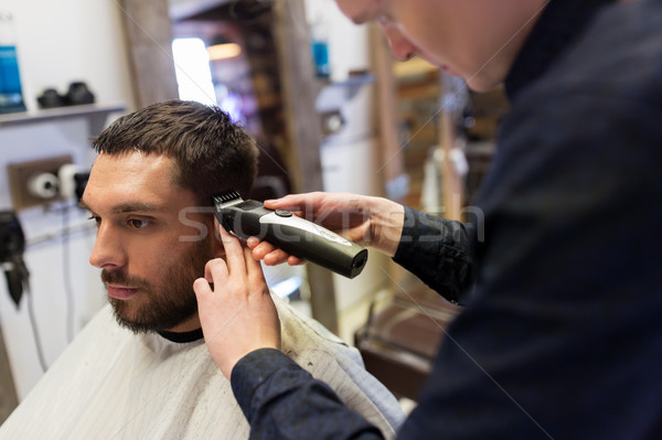 man and barber with trimmer cutting hair at salon Stock photo © dolgachov
