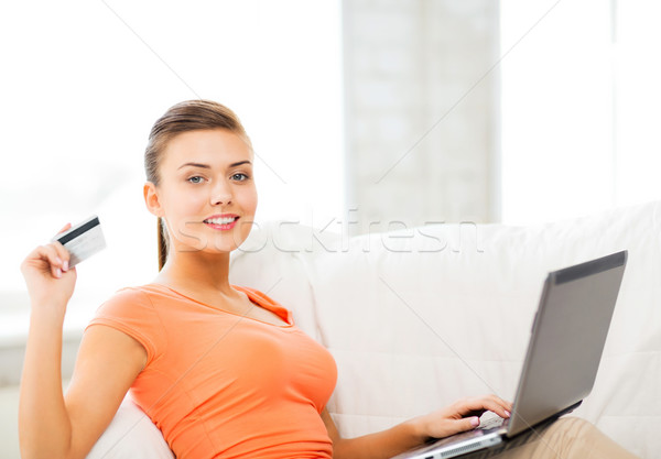 Stock photo: woman with laptop showing credit card at home