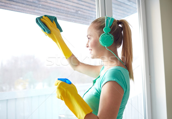 happy woman with headphones cleaning window Stock photo © dolgachov