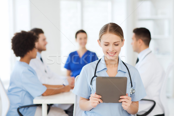 Stock photo: happy doctor with tablet pc over team at clinic