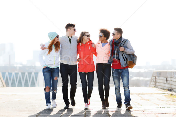 happy teenage friends walking along city street Stock photo © dolgachov