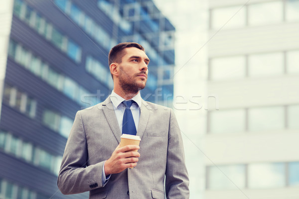 young serious businessman with paper cup outdoors Stock photo © dolgachov