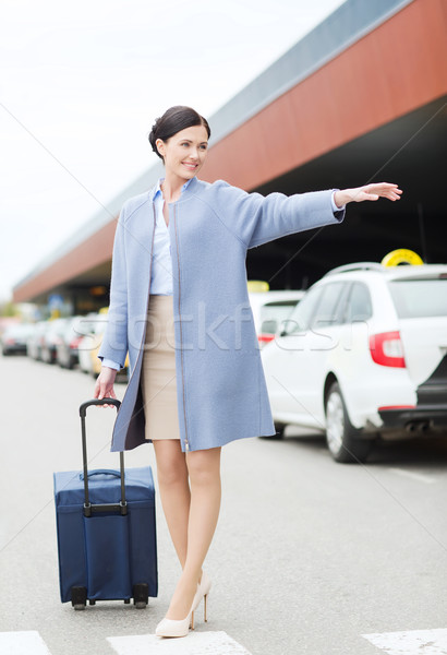 smiling young woman with travel bag catching taxi Stock photo © dolgachov