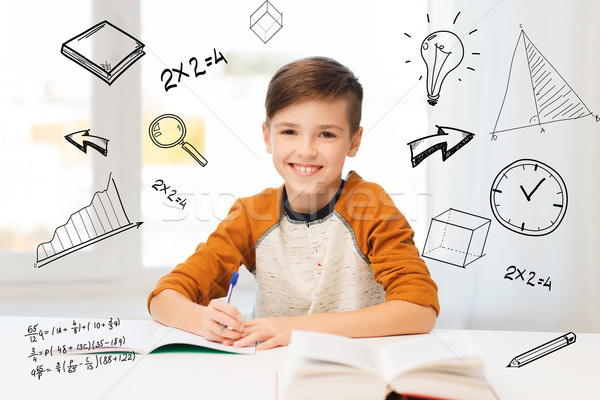 Uśmiechnięty student chłopca piśmie notebooka domu Zdjęcia stock © dolgachov