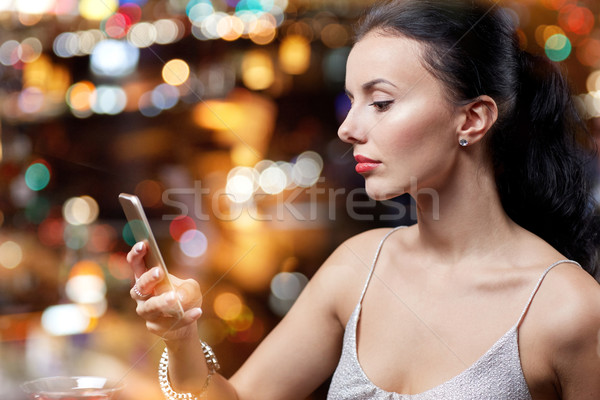 young woman with smartphone at night club or bar Stock photo © dolgachov
