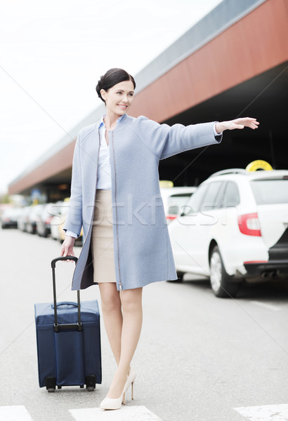 smiling young woman with travel bag catching taxi Stock photo © dolgachov