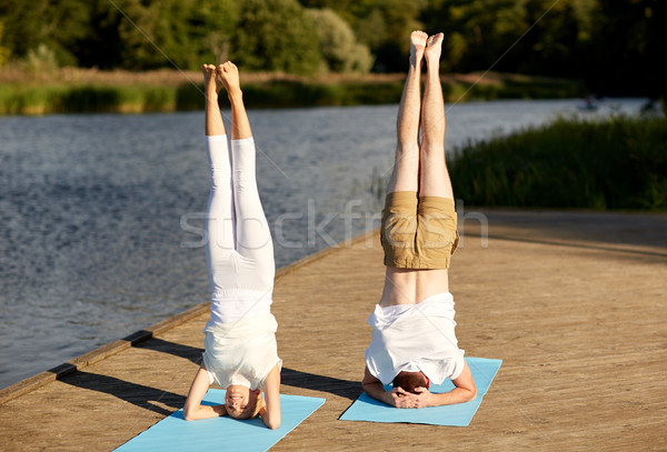 couple making yoga headstand on mat outdoors Stock photo © dolgachov