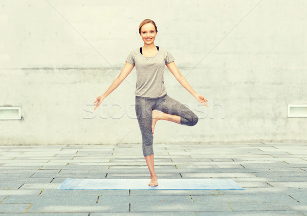 woman making yoga in tree pose on mat Stock photo © dolgachov