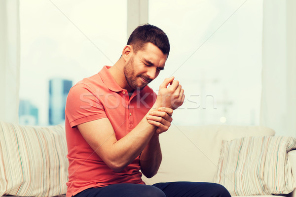 unhappy man suffering from pain in hand at home Stock photo © dolgachov